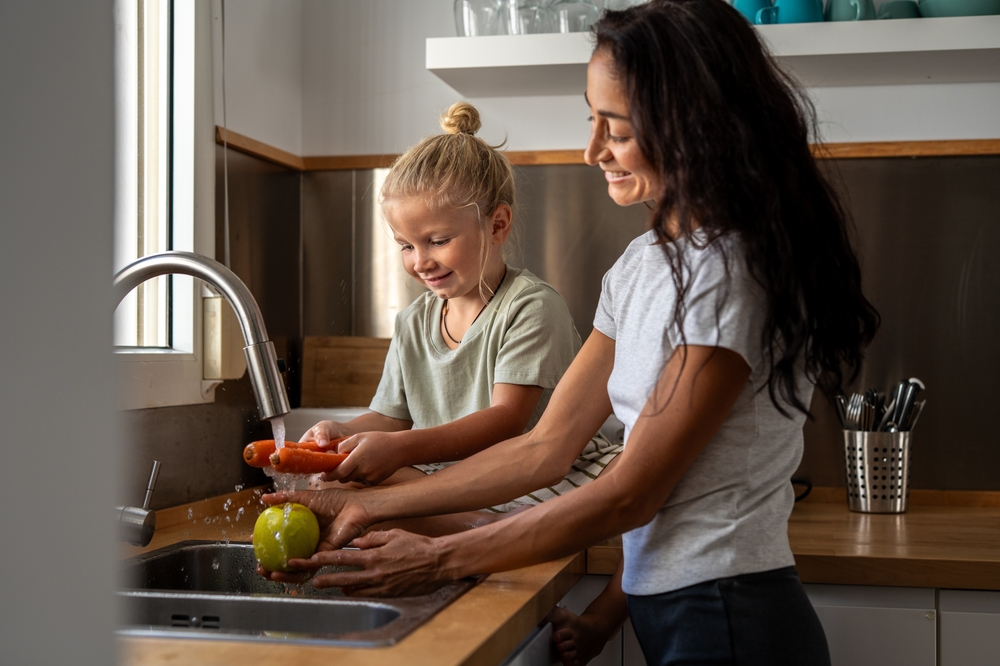 family washing food in kitchen